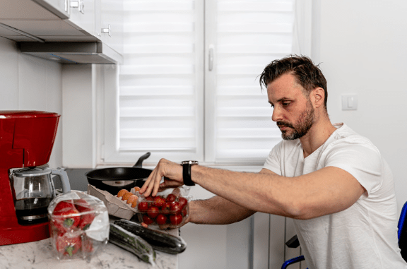 Wheelchair user in his adaptive kitchen preparing a meal