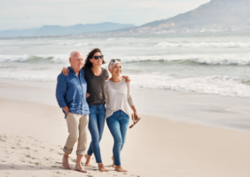 Elderly couple and daughter walking on the beech