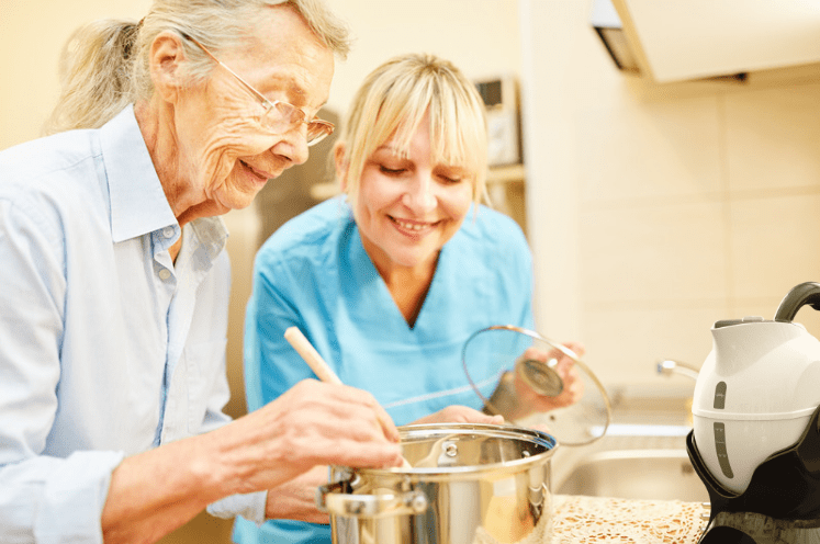 occupational therapist in the kitchen with elderly woman cooking