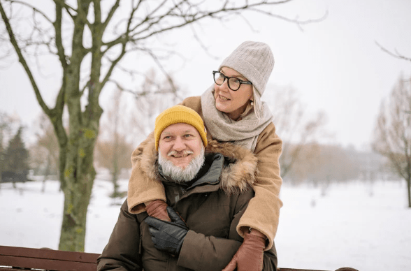 Elderly couple sitting on a bench in the snow