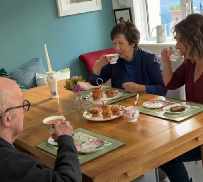 Adult daughter enjoying tea and cake with her mother and father