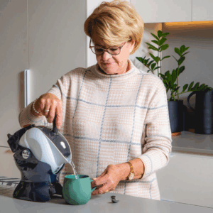 Elderly woman making tea with the Uccello Tipping Kettle