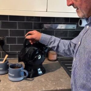 Elderly man in the kitchen pouring 2 cups of tea with the all black uccello kettle