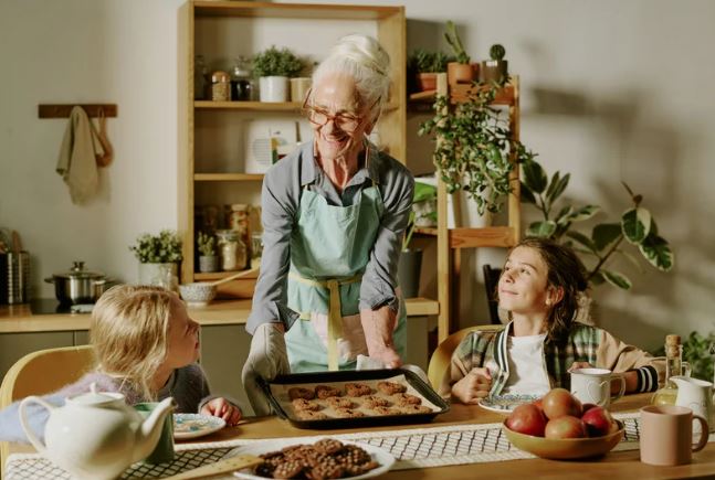 Grandmother in the kitchen baking with her 2 grandchildren