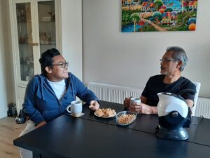 Father and son enjoy a cup of tea and cake together in the dining room