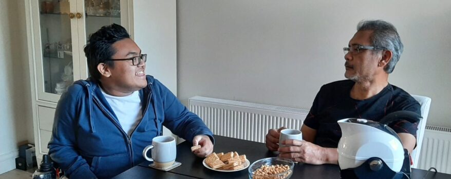 Father and son enjoy a cup of tea and cake together in the dining room